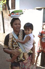 Frau mit Schssel auf dem Kopf und Kind im Arm in Bagik Nunggal