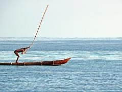 Numfor: Mit dem Boot um die ganze Insel - Fischer schlgt mit der Stange aufs Wasser, um Fische ins Netz zu treiben